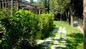 A stone pathway leading through a garden with a pergola structure and dense greenery. - Belvilla by OYO Montaione Bilo Quattro (Montaione)