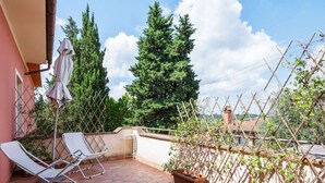 A patio with two white lounge chairs, a brick floor, and potted plants. - Belvilla by OYO Montaione Bilo Quattro (Montaione)