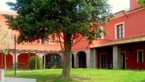 A building with a red facade, a central courtyard with a large tree, and a covered outdoor seating area. - Belvilla by OYO Montaione Bilo Quattro (Montaione)