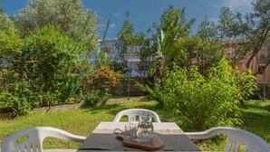 A table set outdoors with a pitcher and glasses, surrounded by greenery and a building in the background. - Holiday Home in Gallura Near White Sandy Beach (Santa Teresa di Gallura)