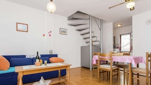 Ett vardagsrum med en blå soffa, ett träbord och en matplats med en rosa duk.
