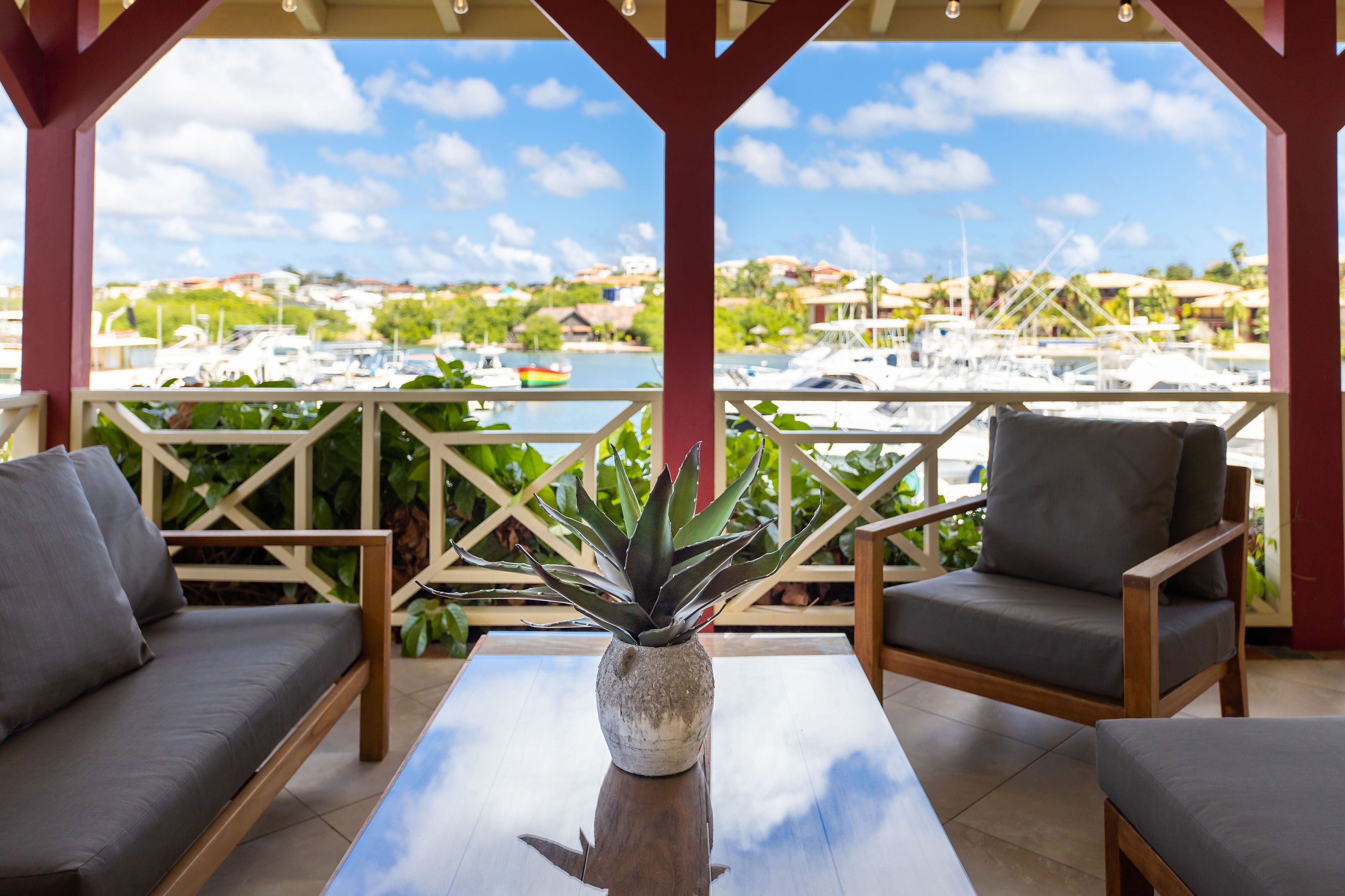 A covered outdoor seating area with a view of a marina and houses in the background.