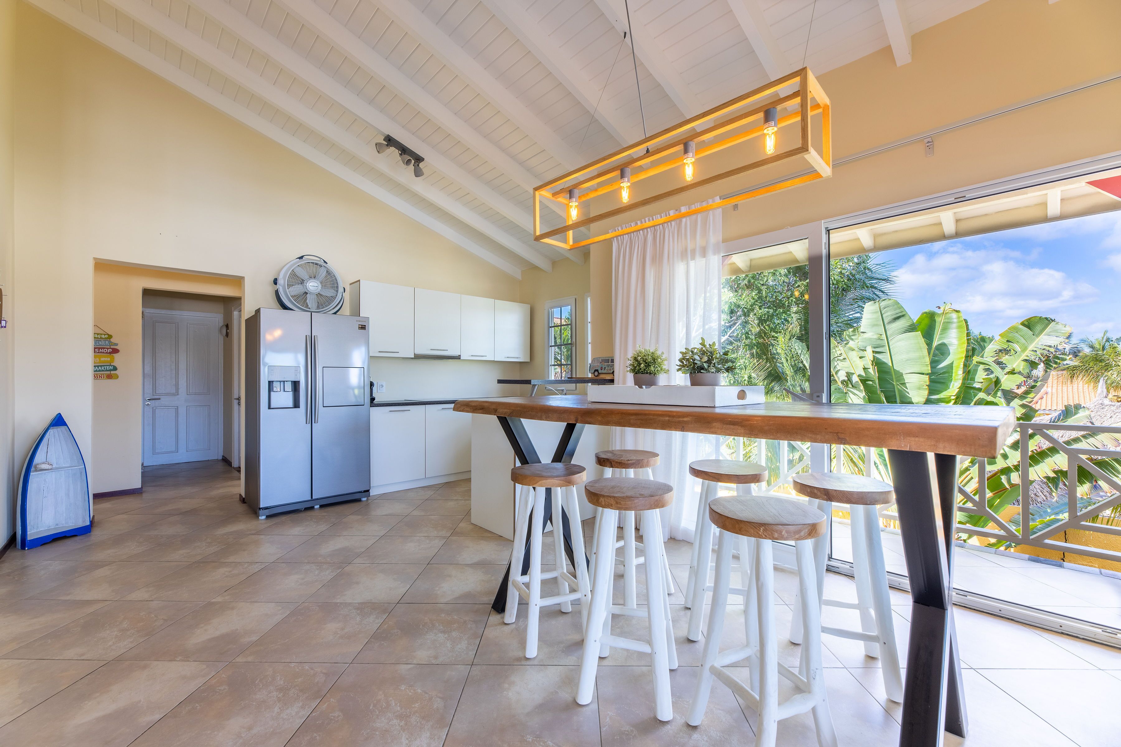 Een moderne keuken met een groot eiland, witte kastjes en uitzicht op de omgeving.