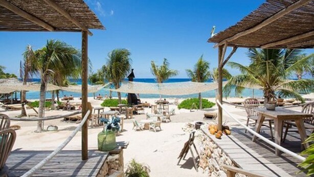 A beachside resort with thatched-roof structures, outdoor seating, and palm trees. - Spanish Water Marina Apartments (Jan Thiel)