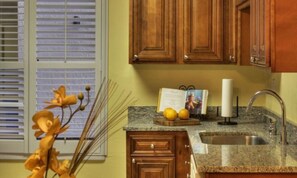 Kitchen with a window, sink, and countertop, featuring a vase and a book.