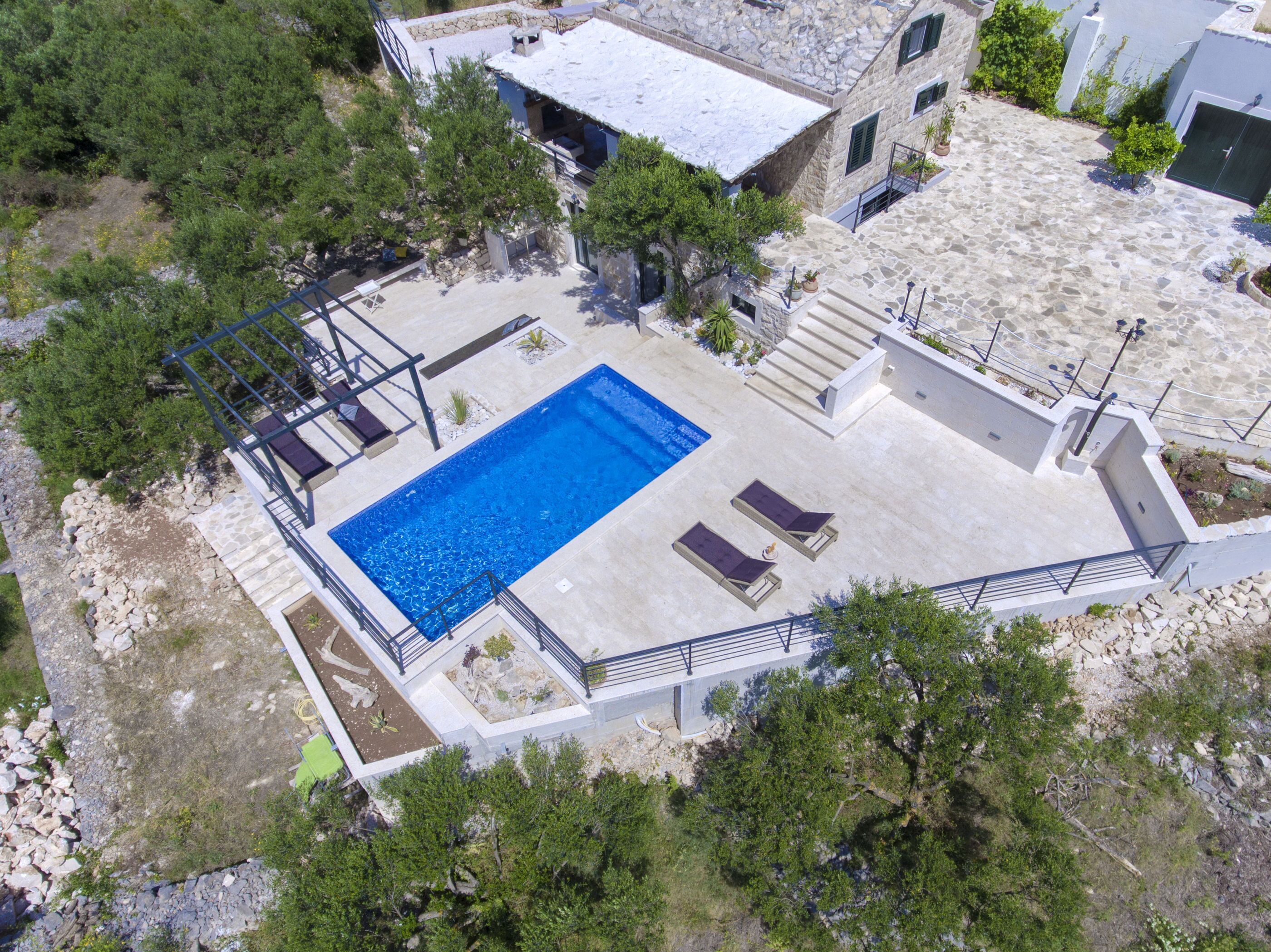 Vue aérienne d’une propriété dotée d’une piscine, de bâtiments en pierre et d’un environnement verdoyant.