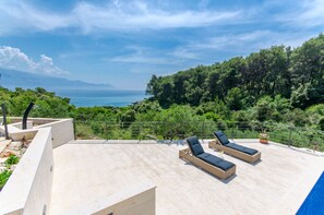 A rooftop terrace with two sun loungers, a swimming pool, and a view of the sea and forest. - Villa Rokova Vala (Sumartin)