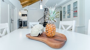 Een eettafel met een houten plank waarop een ananas en een schelp liggen.