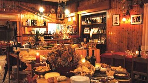 A warmly lit dining area with wooden walls, a variety of food and drink items on tables, and a Christmas tree centerpiece. - Peaceful Stay With Garden (Alto Reno Terme)