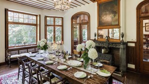 A dining room with a long wooden table set for a meal, large windows, and a fireplace. - Beautiful Castle in Spa wit Garden (Spa)