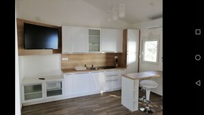 Een moderne keuken met witte kastjes, een houten aanrecht, een spoelbak en een barkruk.