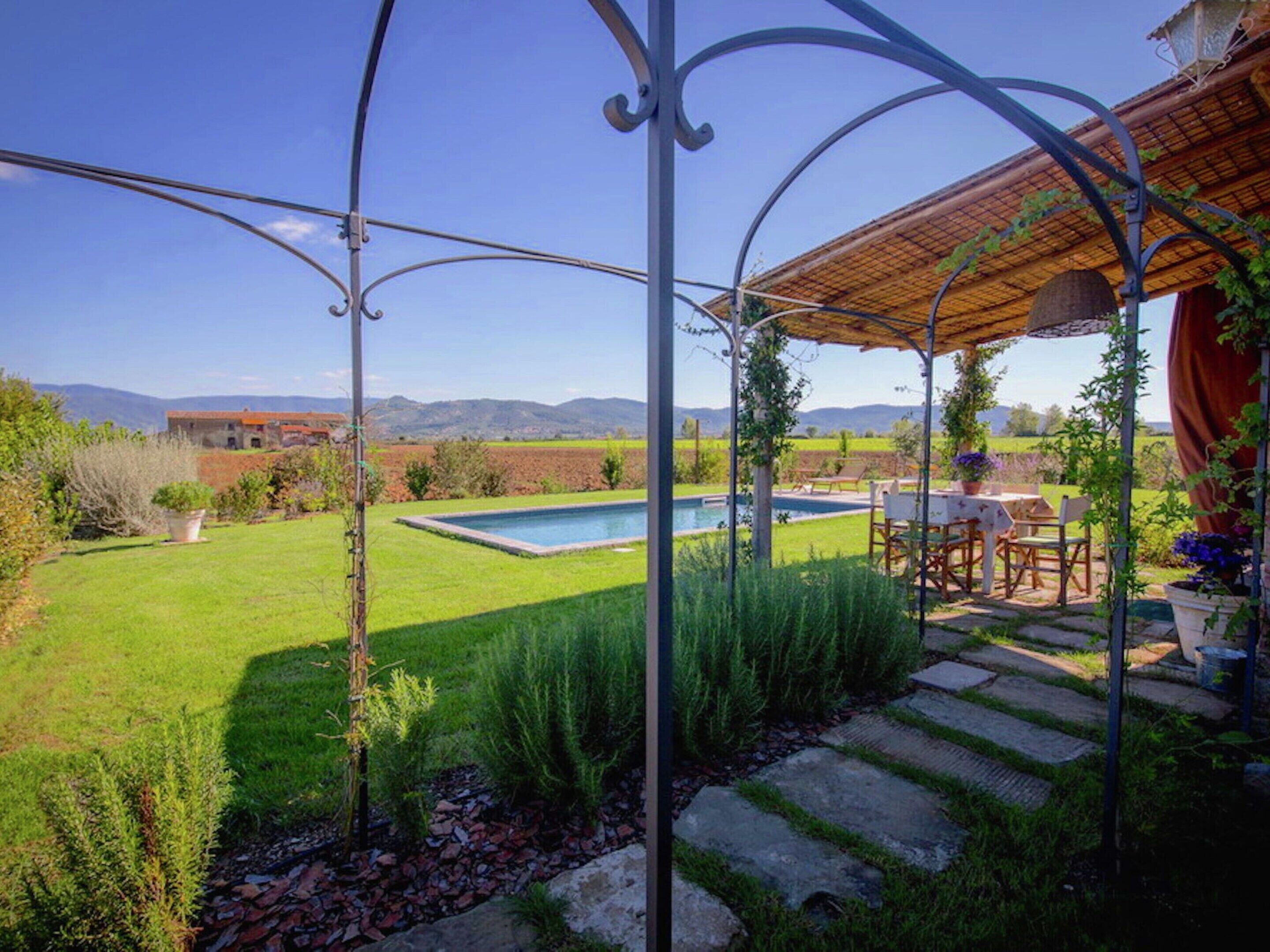 A backyard with a swimming pool, stone pathway, and outdoor furniture.