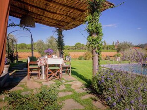 An outdoor patio with a table and chairs, surrounded by greenery and a view of the countryside. - 4 Person Villa with Private Swimming Pool & Garden in Lovely Surroundings near Cortona (Cortona)