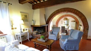 A cozy living room with a fireplace, two armchairs, a sofa, and a coffee table. - Villa in Cortona With Pool & Countryside Views (Cortona)