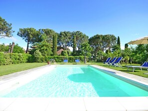 A clear blue pool with a tiled deck, surrounded by green hedges and trees. - Villa in Cortona With Pool & Countryside Views (Cortona)