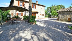 A two-story stone building with a covered patio area featuring outdoor seating. - Villa in Cortona With Pool & Countryside Views (Cortona)