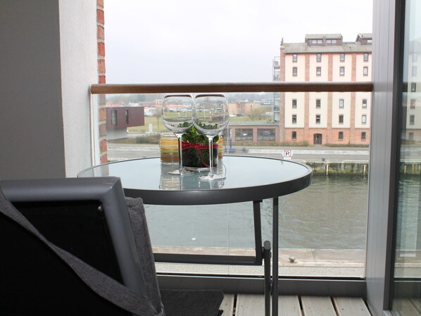 A balcony with a glass table, two wine glasses, and a bottle of wine. - Charmante Ferienwohnung in Wismar am Hafen (Wismar)