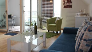 Un soggiorno moderno con un tavolino in vetro, un divano blu, una poltrona verde e un'area pranzo con un piccolo tavolo e sedie.