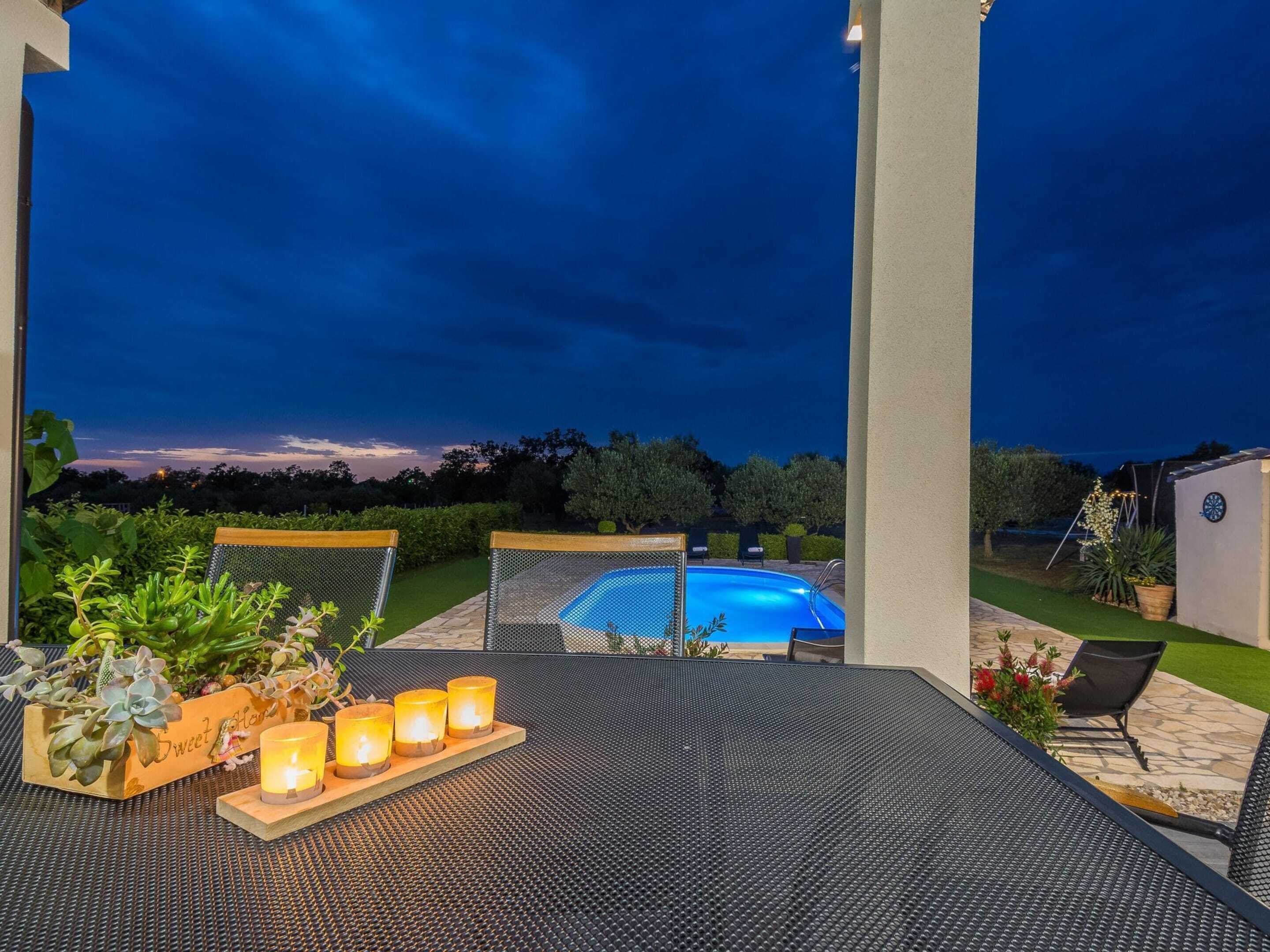 Une terrasse extérieure avec une piscine, entourée de verdure et offrant une vue dégagée sur le ciel.
