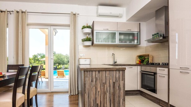 A modern kitchen with a wooden island, a built-in oven, and a sink. - Peaceful Home in Policnik (Policnik)
