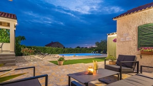 A patio area with outdoor seating, a swimming pool, and a view of a house in the background. - Peaceful Home in Policnik (Policnik)