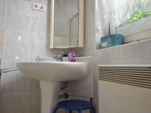 Ein Badezimmer mit Waschbecken, Spiegel und blauem Hocker.