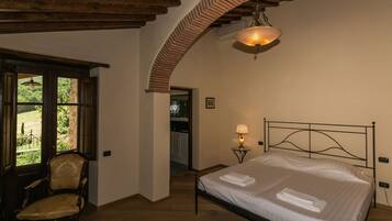 Una camera da letto con un letto, una sedia, una lampada e vista sull'esterno attraverso una finestra.