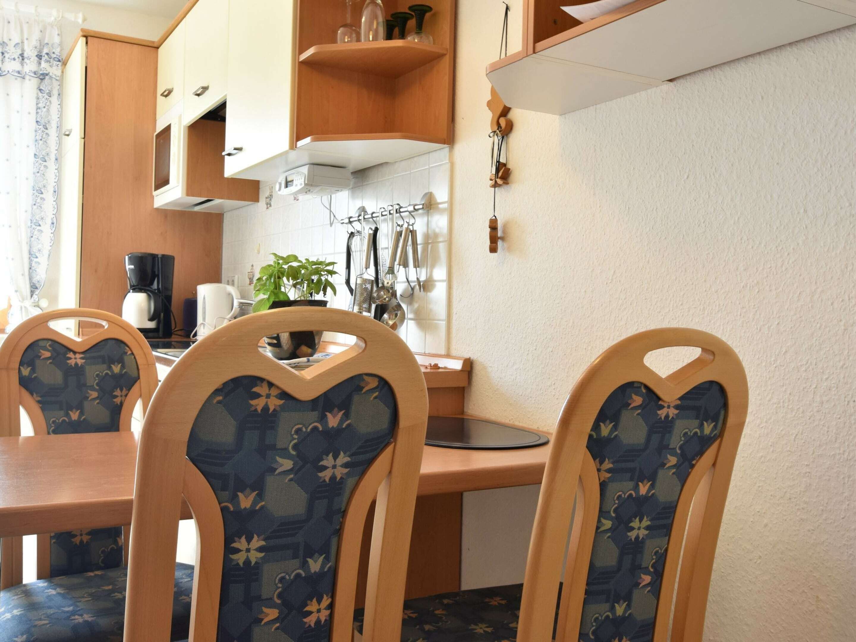 A compact kitchen with wooden cabinets, a coffee maker, and a hanging utensil rack.