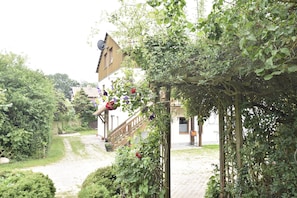 A garden pathway leading to a building with a wooden staircase and a pergola with climbing plants. - Lovely Apartment in Rerik near Baltic Sea Beach (Rerik)