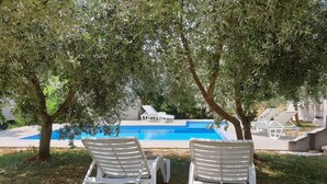 Two white lounge chairs facing a swimming pool with a view of trees and a clear sky. - Holiday Home in Banjole Near the Beach (Medulin)