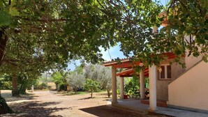 A covered outdoor area with a pergola, a gravel path, and trees. - Holiday Home in Banjole Near the Beach (Medulin)