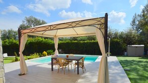 Una veranda coperta all'aperto con tavolo da biliardo, sedie e piscina.