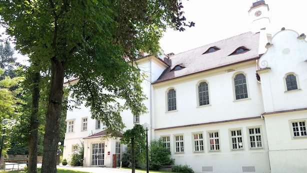 Un grand bâtiment blanc doté de nombreuses fenêtres et surmonté d’une tour horloge.