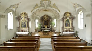 L’intérieur d’une église, avec ses bancs en bois, son autel et ses décorations élaborées.