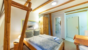 Un dormitorio con estructura de cama de madera, mesita de noche, escritorio y armario.
