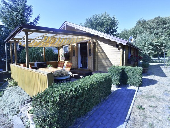 A wooden house with a covered patio, a barbecue area, and a well-maintained garden. - Bungalow in Klein Strtsmkendorf (Am Salzhaff)
