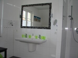 A bathroom with a white sink, green cups, a mirror, and a shower. - Holiday Home in Rerik With Private Terrace (Rerik)