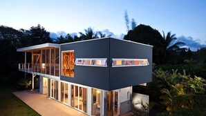Ein modernes, zweistöckiges Haus mit großen Fenstern und einem Balkon.