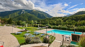A pool area with lounge chairs and a view of mountains. - Belvilla by OYO Sogno (Piobbico)
