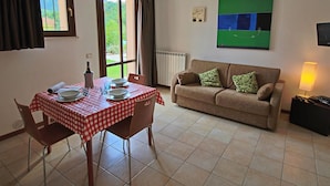 A dining area with a checkered tablecloth, a sofa, and a TV on the wall. - Belvilla by OYO Sogno (Piobbico)
