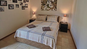 A bedroom with a large bed, two bedside tables, and a wall with framed pictures. - Belvilla by OYO Sogno (Piobbico)