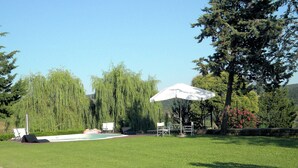 A grassy outdoor area with a pool, lounge chairs, and a white umbrella. - Tuscan Hideaway With Pool (San Casciano dei Bagni)