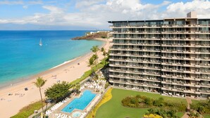 A high-rise hotel with multiple balconies overlooking a beach and ocean. - AEI at The Whaler Kaanapali Beach Resort (Lahaina)