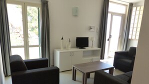 A modern living room with a sofa set, a TV, and a small table. - Apartment in Tropea With Sea Views & Pool (Parghelia)