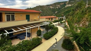 A hillside property with a covered patio, a winding pathway, and a view of the surrounding hills. - Apartment in Tropea With Sea Views & Pool (Parghelia)