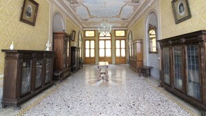 A grand hall with a central table, arched windows, and ornate wood paneling. - Castle in Veneto With Garden & History (Romano d'Ezzelino)