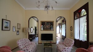 A living room with floral-patterned sofas, a flat-screen TV, and a chandelier. - Castle in Veneto With Garden & History (Romano d'Ezzelino)
