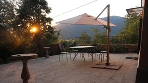 An outdoor patio with a table and chairs, a large umbrella, and a stone fountain. - Castle in Veneto With Garden & History (Romano d'Ezzelino)