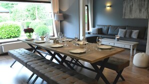 A dining area with a wooden table set for four, a bench, and a sofa in the background. - Luxurious Holiday Home in Hamoir With Terrace (Hamoir)