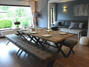 A dining area with a wooden table set for four, a bench, and a sofa in the background. - Luxurious Holiday Home in Hamoir With Terrace (Hamoir)